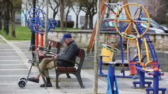 Un anciano sentado en un banco de un parque de Ondarroa.