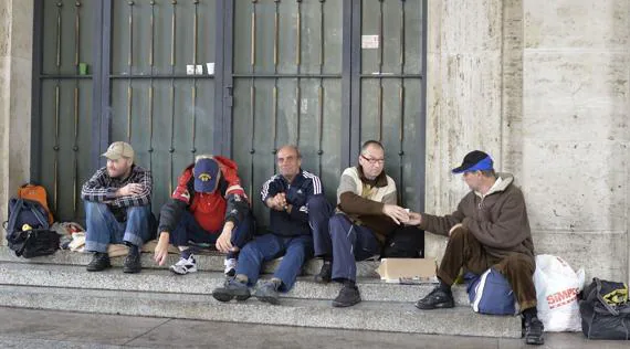 Un grupo de hombres sin hogar hablan en unas escaleras en el Vaticano.