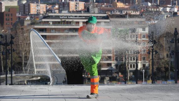 Un operario esparce sal  en una calle de Bilbao.