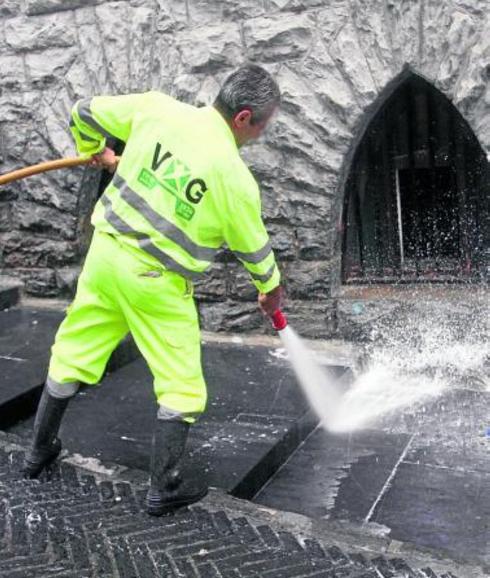 Un trabajador limpia con una manguera el suelo del Casco.