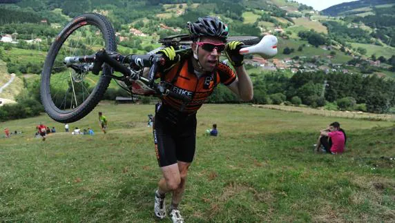 Participante en la maratón carga con su bici.