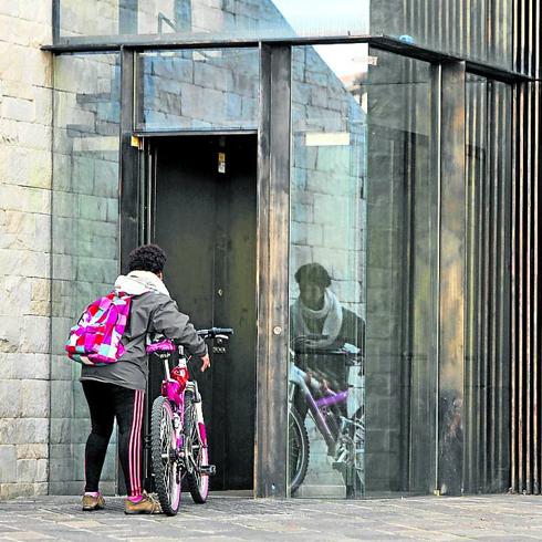 Una ciclista accede al ascensor por la calle Correría.