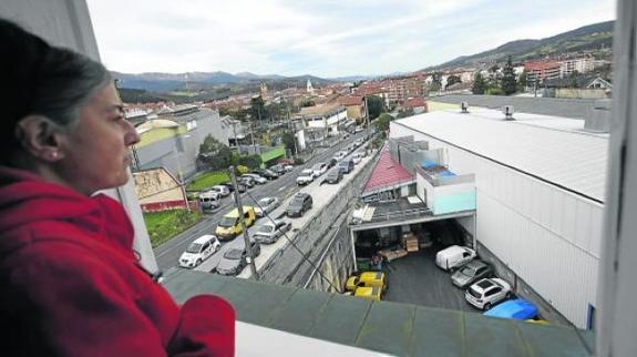 Una vecina observa desde la ventana la fábrica situada a escasos metros de su casa. 