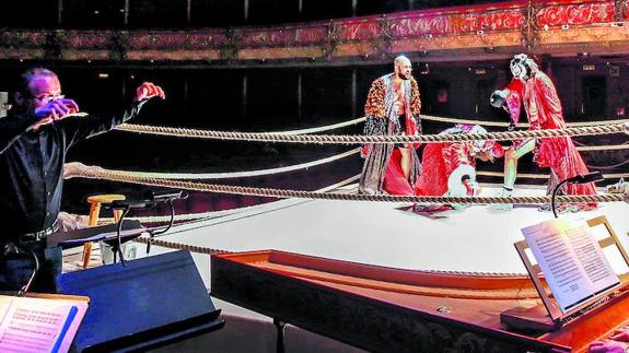 El maestro Fausto Nardi, al frente de la orquesta barroca, dirige la música que acompaña el combate de boxeo en mitad del escenario.