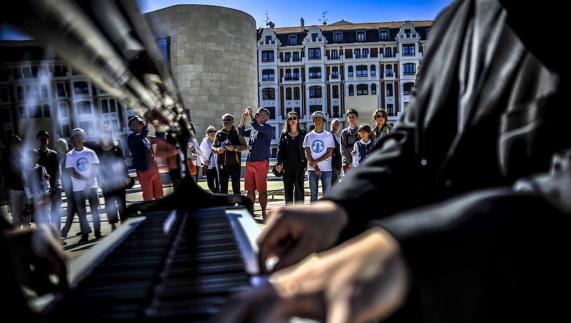 Un grupo de personas escucha la música de uno de los pianistas. /IGNACIO PÉREZ