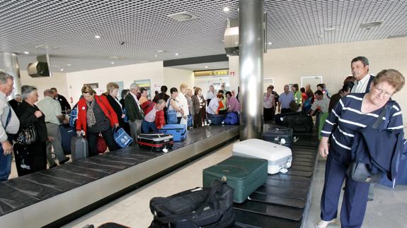 Pasajeros recogen su equipaje al salir del avión.