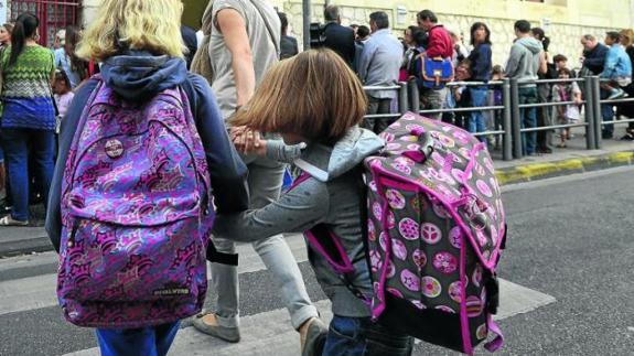 Un grupo de niños con sus familiares, a la entrada de un centro escolar. 