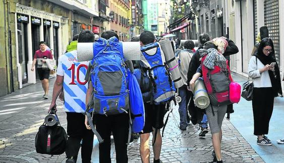 Un grupo de turistas se adentra con sus mochilas por la calle Correo del Casco Viejo.