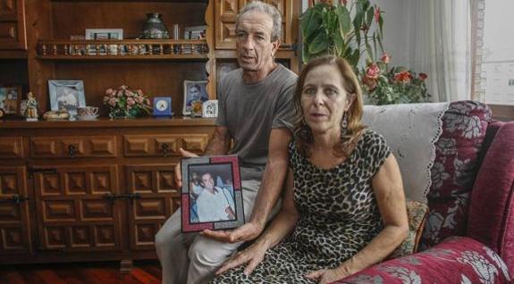 Juan y María, los padres de Cristian, posan con una foto del surfista en su residencia temporal de Torrelavega. 