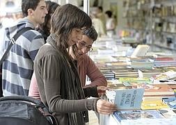 Dos visitantes de la feria ojean un libro. /B. Agudo. Vídeo: Daniela Velasco-Zuriñe Palacio
