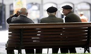 Tres jubilados conversan sentados en un banco de un parque./ E.C