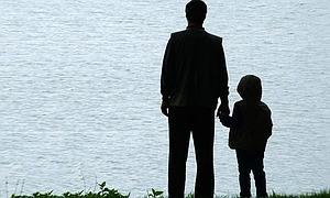 Un padre y su hijo, de la mano, frente al mar.