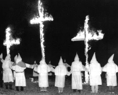 DERROTADOS. Miembros del Ku-Klux-Klan rodean cruces en llamas en una de sus reuniones. / EL CORREO