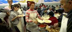 Los voluntarios, entre ellos varias estudiantes, sirven lentejas y pechugas de pollo con pimientos y tomate en el comedor de Irala. / MITXEL ATRIO