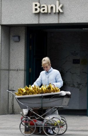 Una mujer utiliza un coche de bebé para vender plátanos frente al Anglo-Irish Bank. ::
REUTERS