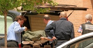 Miembros de una funeraria trasladan el cadáver de la madre, Pilar, de 58 años, en presencia de un agente de la Ertzaintza. ::                             LUIS CALABOR