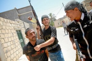 Dos rebeldes libios capturan a un presunto francotirador del régimen de Gadafi en un barrio de la ciudad de Zauiya. ::
AFP