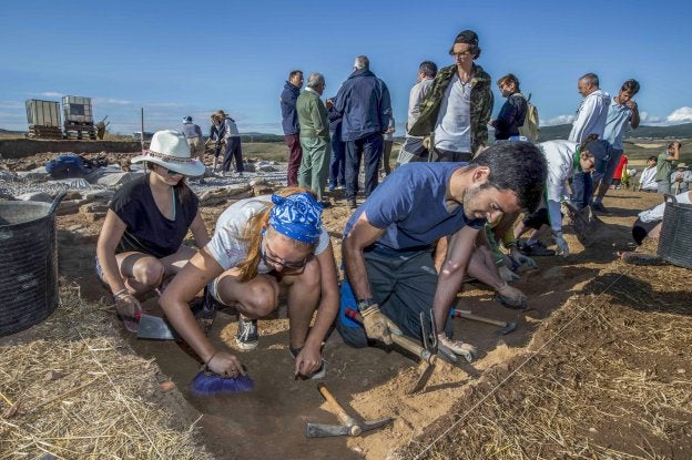 Jóvenes participantes en el campo de trabajo y arqueólogos, en el yacimiento de La Cueva, en Camesa-Rebolledo (Valdeolea).