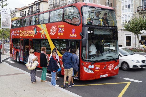 Los turistas suben al autobús en pleno Paseo de Pereda. No es un día soleado, así que no falta el chubasquero.