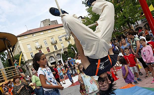 Uno de los integrantes del grupo circense enseña a una niña como colgarse del trapecio de una manera profesional ante la atenta mirada del resto de los pequeños