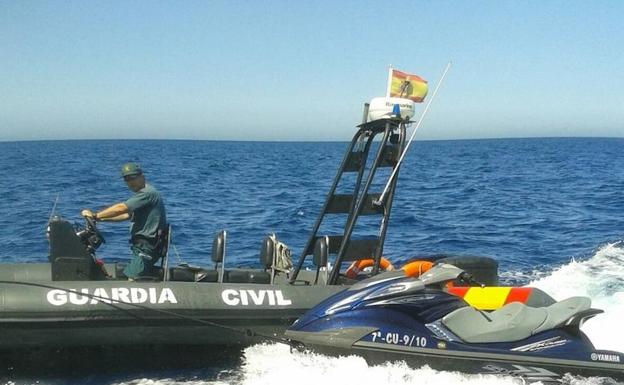 Una embarcación de la Guardia Civil remolca una moto de agua interceptada en el Estrecho.