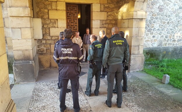 Guardia Civil y Policía Local junto al párroco y carpinteros en la puerta dañada de la iglesia