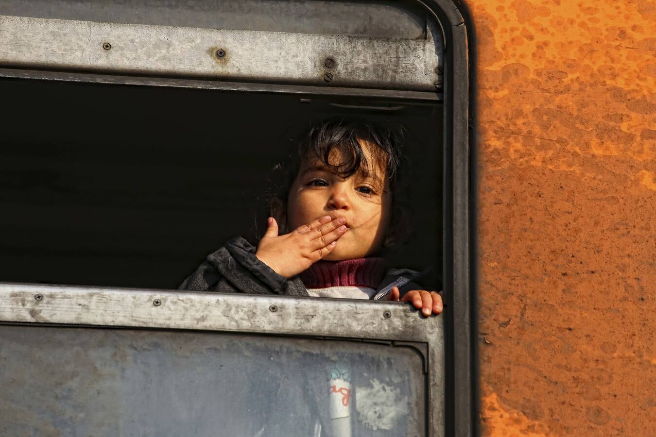 Una niña refugiada lanza un beso desde la ventanilla del tren en el que viajaba con dirección a la frontera de Serbia. (Foto: Ángel Colina)