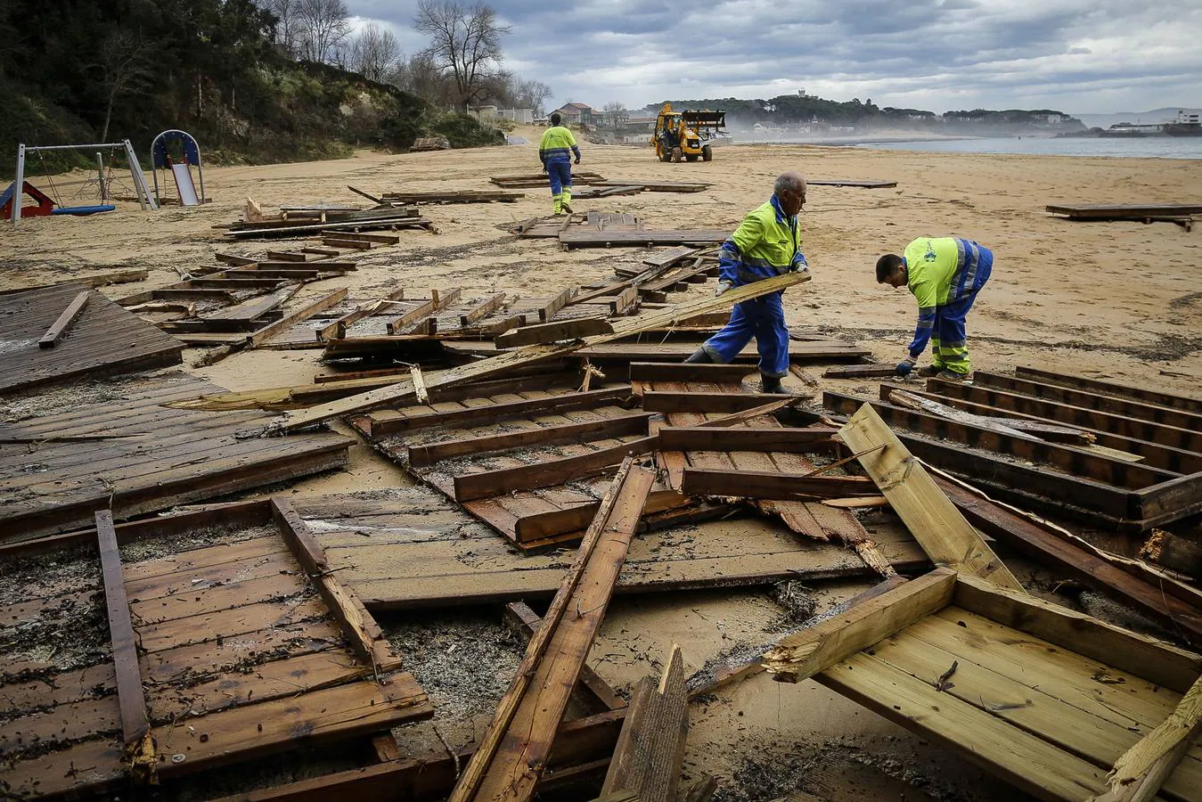 Operarios municipales recogiendo maderas en la playa de Los Peligros de Santander debido a los destrozos por el temporal marítimo. (Foto: Nacho Cubero)