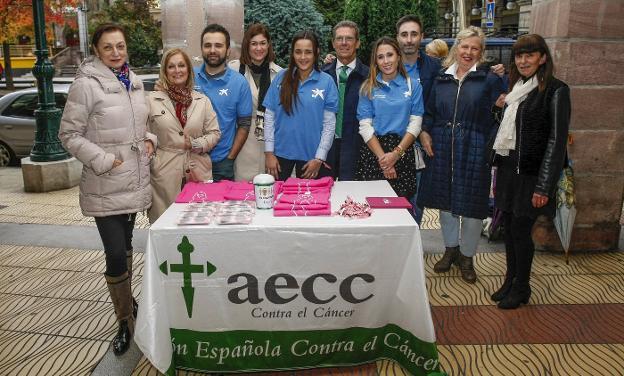 Voluntarios de la AECC y empleados de 'la Caixa', ante una de las mesas dispuestas en la plaza Mayor de Torrelavega.