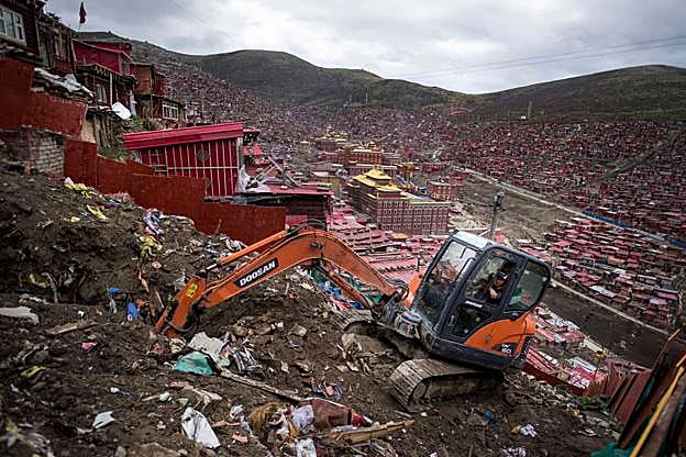 Una excavadora derriba una barriada de chabolas en el extrarradio de una ciudad china. 