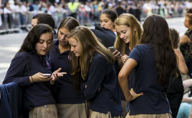 Una estudiante muestra a sus compañeras el contenido de un mensaje en su teléfono. 