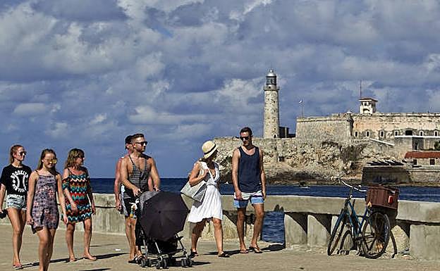 uristas caminan por el Malecón habanero. 