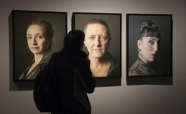 Un hombre observa tres retratos de la exposición.
