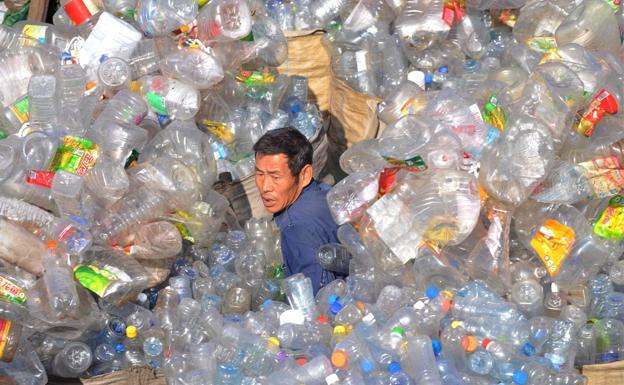 Colapso. Un trabajador de una planta de tratamiento de residuos plásticos de Shenyang, al noreste de China, trata de abrirse paso entre un océano de envases. 