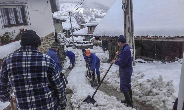 Varias personas retiran la nieve de las calles para facilitar el tránsito a los vecinos de Barrio, en Vega de Liébana. 