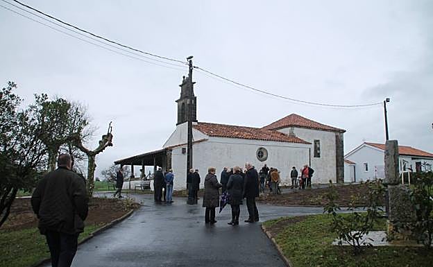 Autoridades y vecinos ante la iglesia de Orejo y al fondo la vivienda que ha sido rehabilitada.