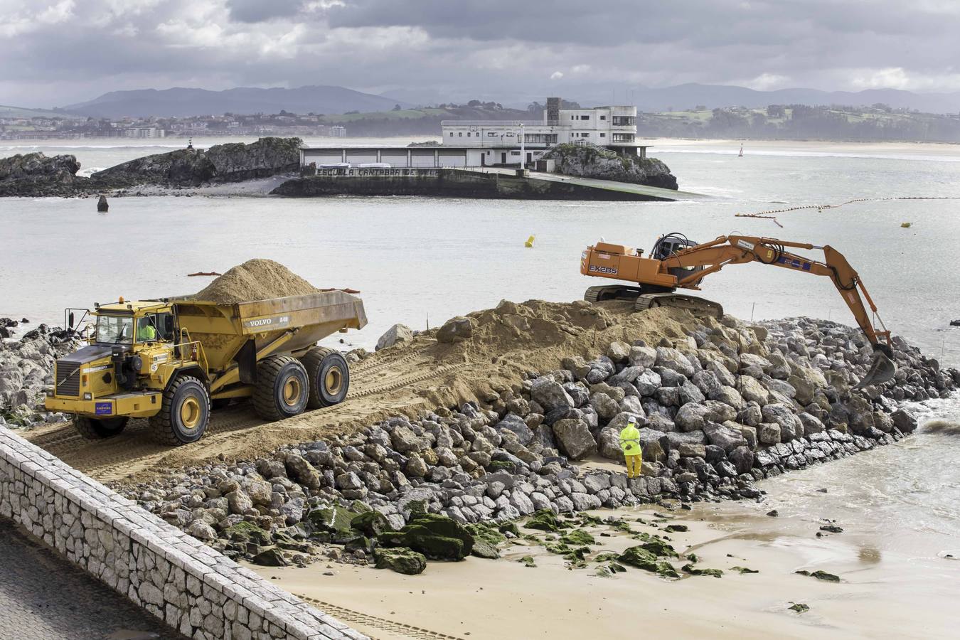 El primer dique para contener la arena ya asoma de forma evidente en La Magdalena.Con la playa cortada y la marea baja, la pala da forma al primero de los espigones, que llama la atención de los curiosos que se acercan a verlo 