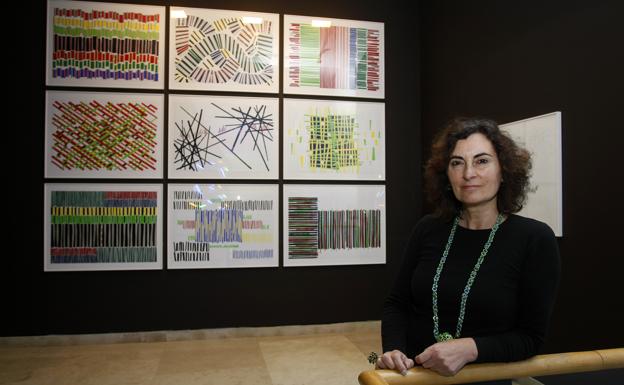 La artista Arancha Goyeneche –vestida de rojo y negro en homenaje a los colores utilizados en Altamira–, posa frente al mural que reproduce la entrada a la cueva. 