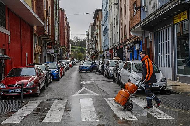 Un repartidor de bombonas de gas camina por un paso de peatones en la calle Torres Quevedo, en La Inmobiliaria.