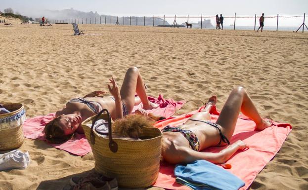 Dos mujeres toman el sol en la playa de La Magdalena.