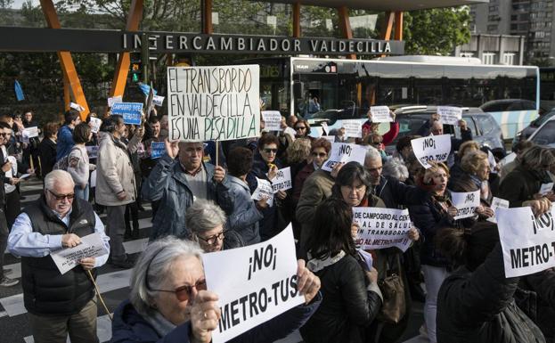 Los vecinos cruzan la calle con sus pancartas de un intercambiador a otro en Valdecilla.