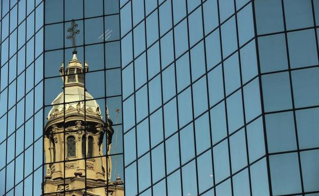 Vista de una de la cúpulas de la catedral de Santiago reflejada en un edificio. 