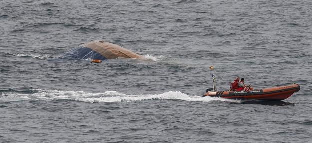 Una lancha de la Cruz Roja navega cerca de la proa de la draga 'Barlovento Primero' antes de que el barco se hundiera por completo.