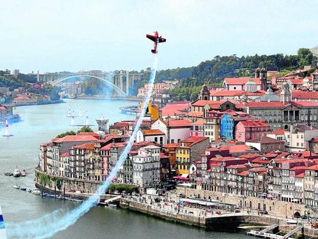 Una avioneta hace una espectacular acrobacia sobre el río Duero, a su paso por Oporto.