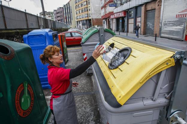 Una empleada de hostelería deposita un envase en un contenedor de la calle Hermilio Alcalde del Río. 