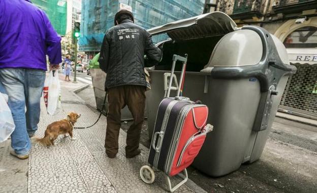 Una persona busca en un contenedor de la calle Cervantes de Santander.