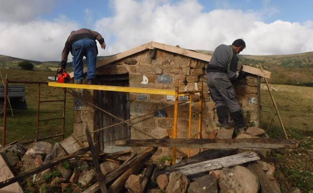 Operarios contratados por el Ayuntamiento llevan obras de rehabilitación en una cabaña. 