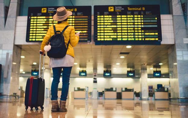 Una turista consulta el panel de destinos en un aeropuerto. :: r. c.