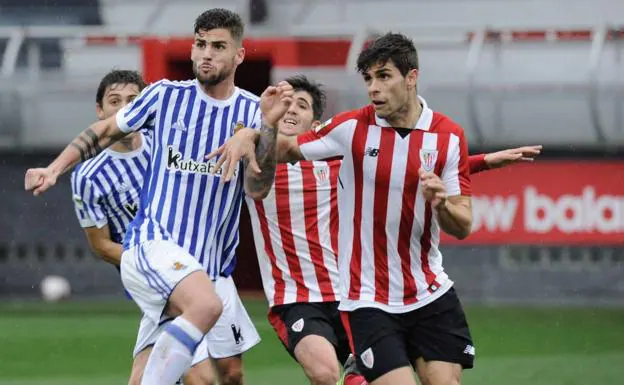 Óscar Gil, en primer término y vistiendo la camiseta del filial del Athletic, pugna con un balón con Jauregi (Real Sociedad B).