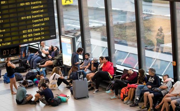 Pasajeros esperan ante un panel con vuelos cancelados en el aeropuerto de Berlín Schönefeld.